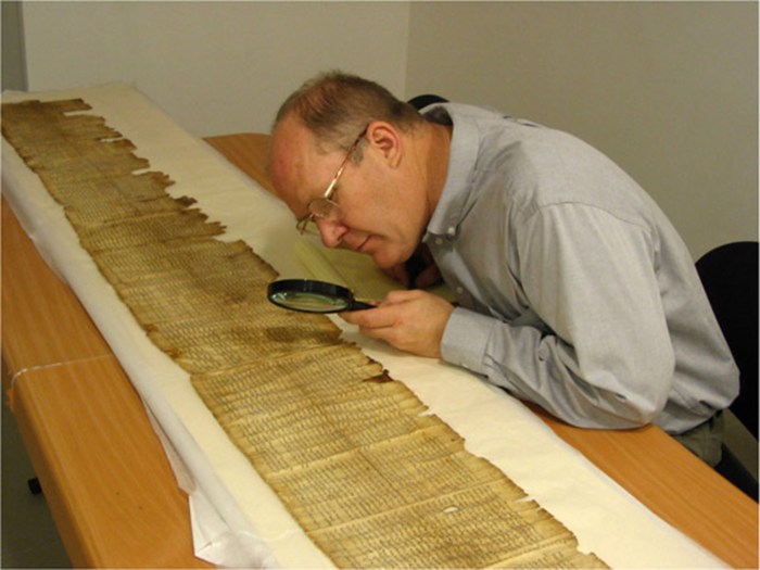 No, he's not a 2000 election worker looking for hanging chads. He is examining a scroll of Scripture!